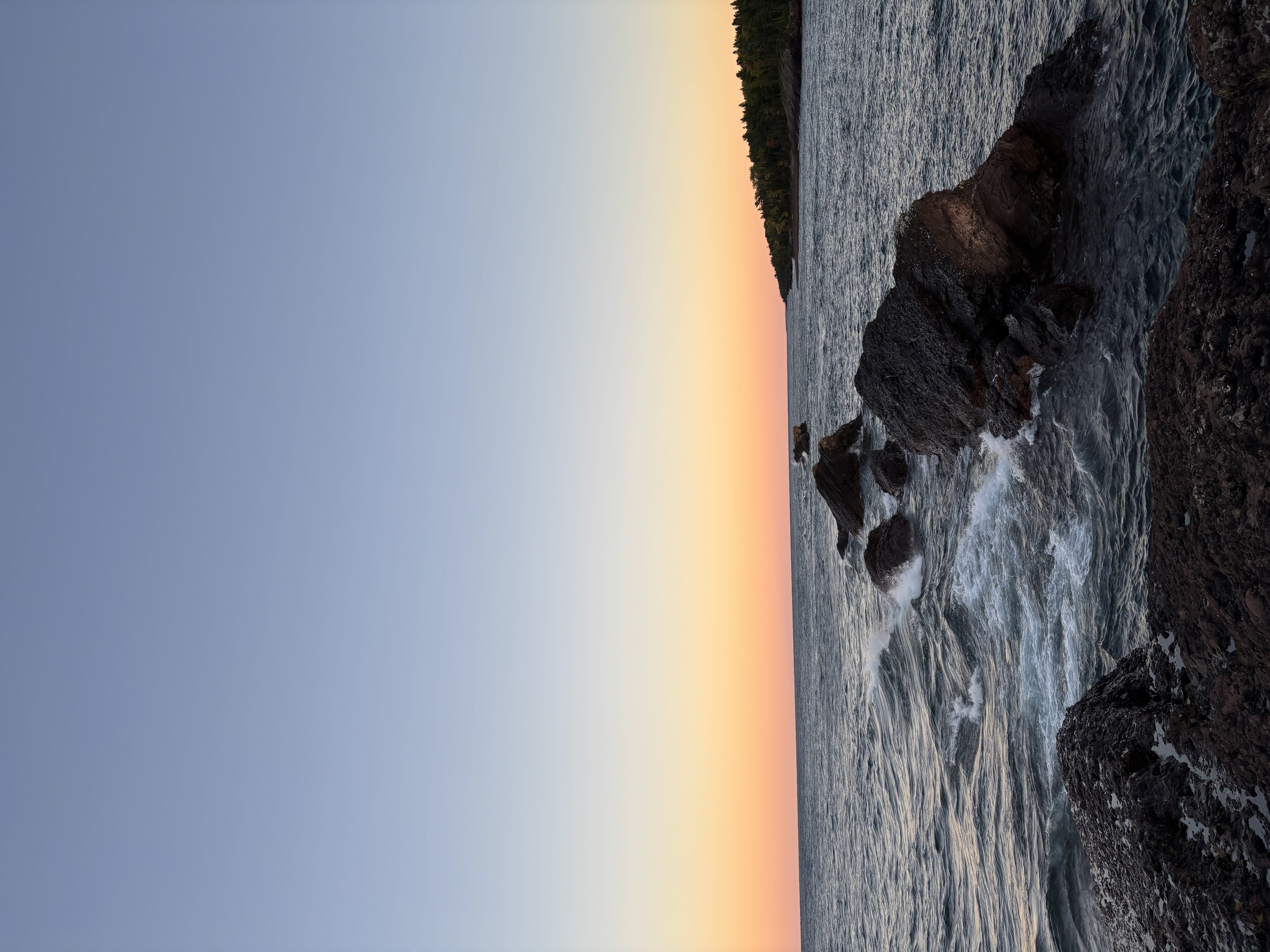 Coastal sunset over rocks and water